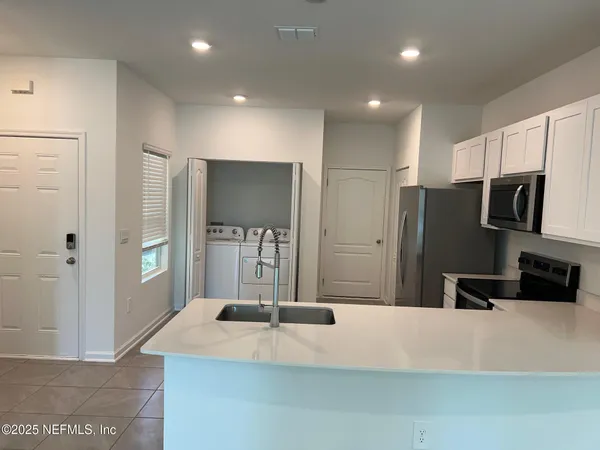 a large kitchen with stainless steel appliances granite countertop a refrigerator and a sink