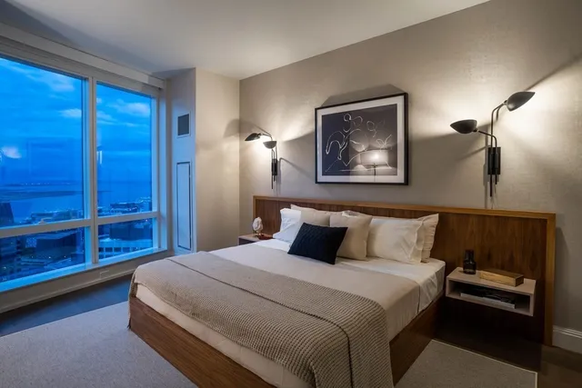 a bedroom with a bed and a lamp on dresser