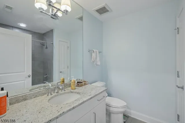 a bathroom with a granite countertop sink a toilet and a mirror