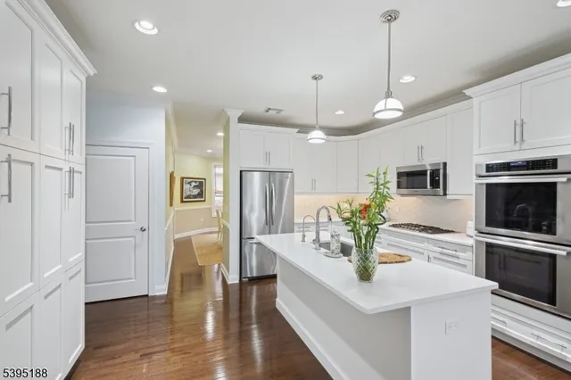 a kitchen with stainless steel appliances kitchen island granite countertop a refrigerator a stove a microwave oven a sink with island and chairs