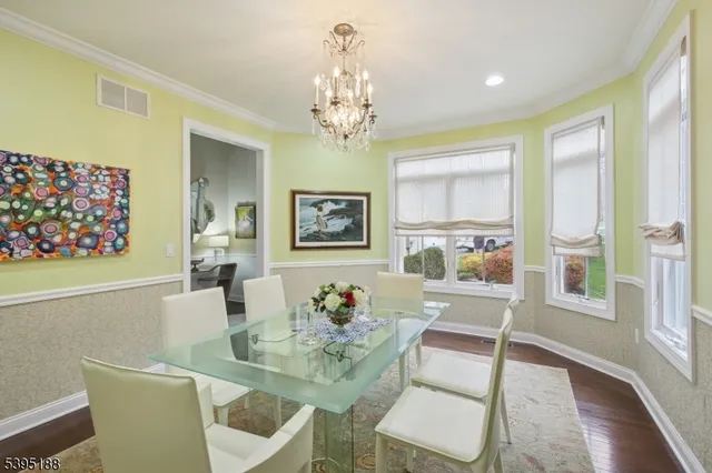 a dining room with wooden floor a chandelier a glass table and chairs