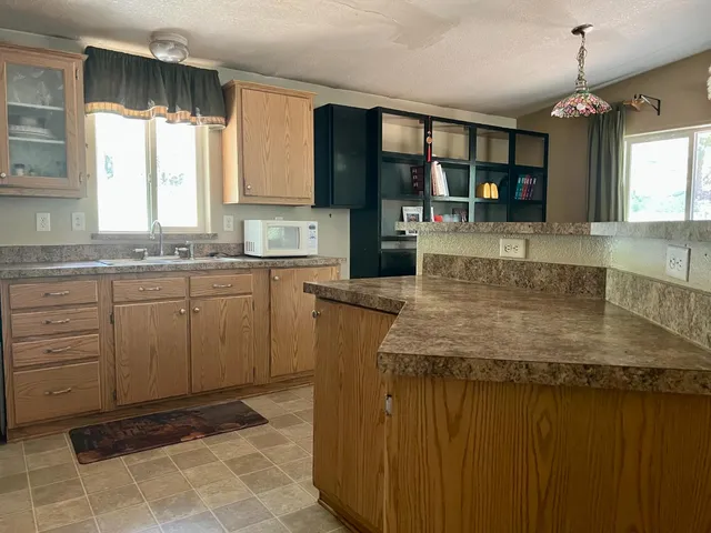 a kitchen with kitchen island granite countertop a sink window and cabinets