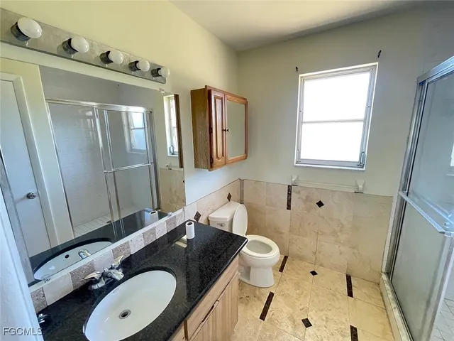 a bathroom with a sink and mirror with toilet