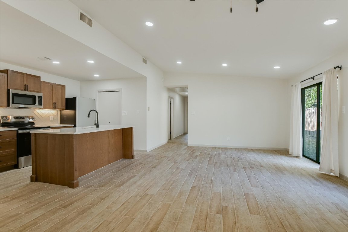 8415 Fathom Circle, Unit B Austin, TX 78750 - Photo 16 of 17 a large kitchen with stainless steel appliances granite countertop a large counter top a wooden floors and a large window
