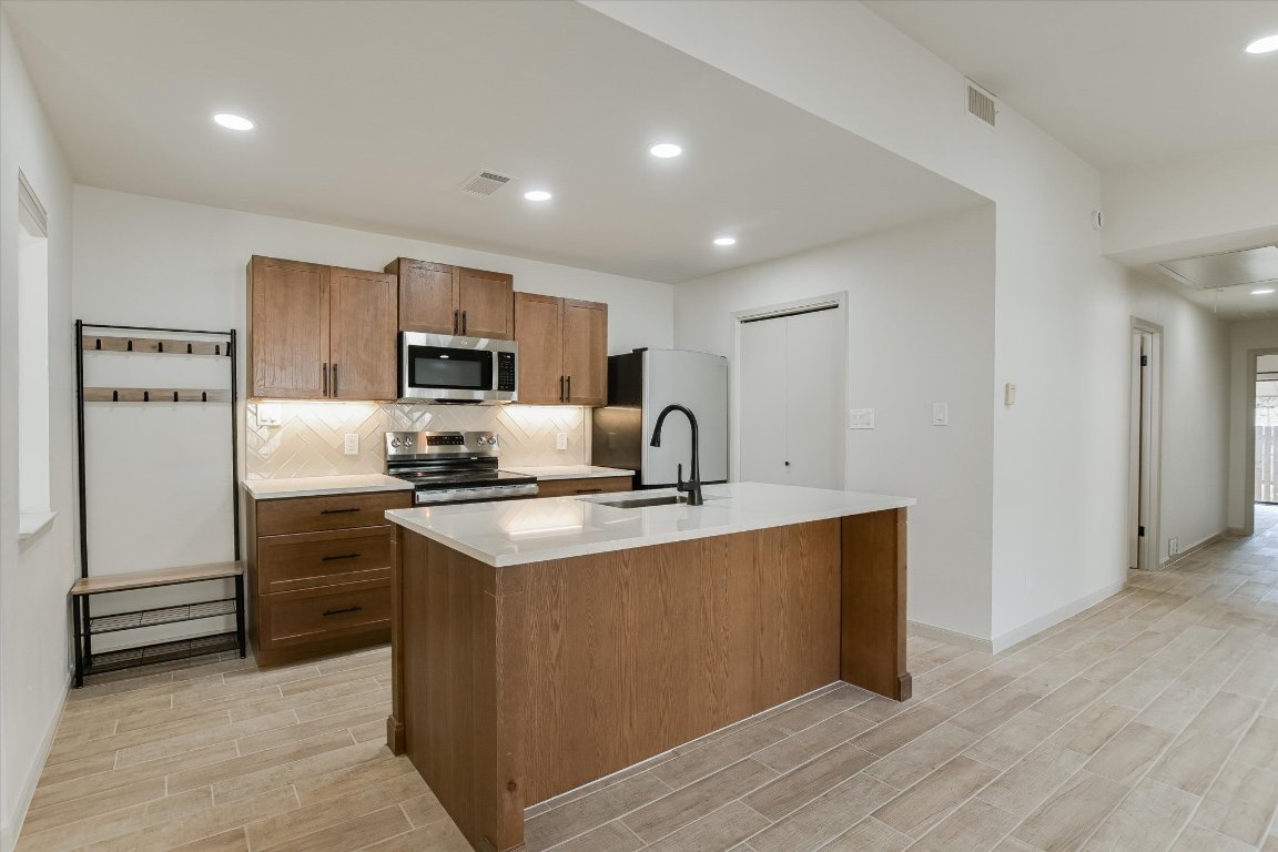 8415 Fathom Circle, Unit B Austin, TX 78750 - Photo 2 of 17 a kitchen with kitchen island a sink stainless steel appliances and cabinets