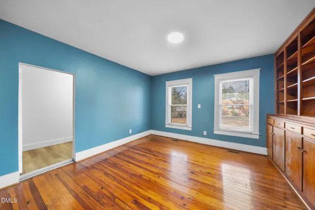 a view of an empty room with glass door and wooden floor