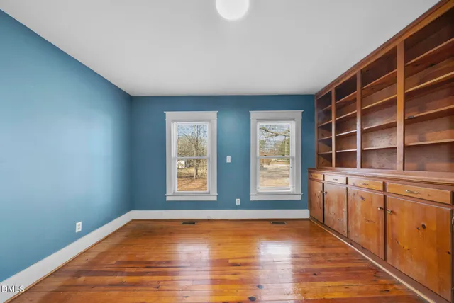 a view of an empty room with window and wooden floor