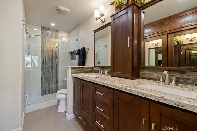 a bathroom with a granite countertop double vanity sink and a mirror
