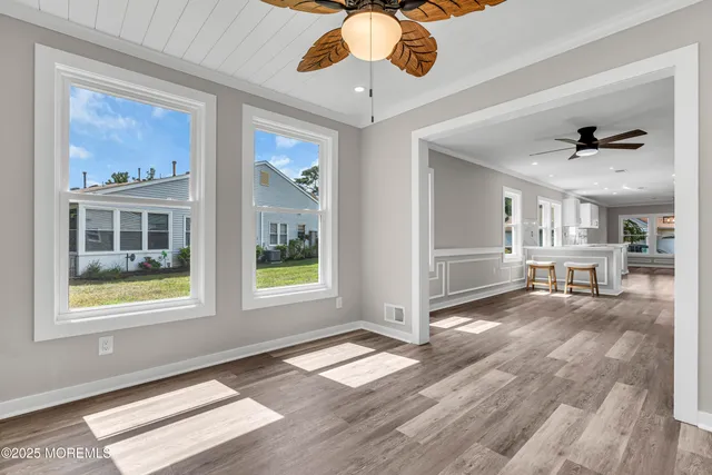 an empty room with wooden floor ceiling fan and windows