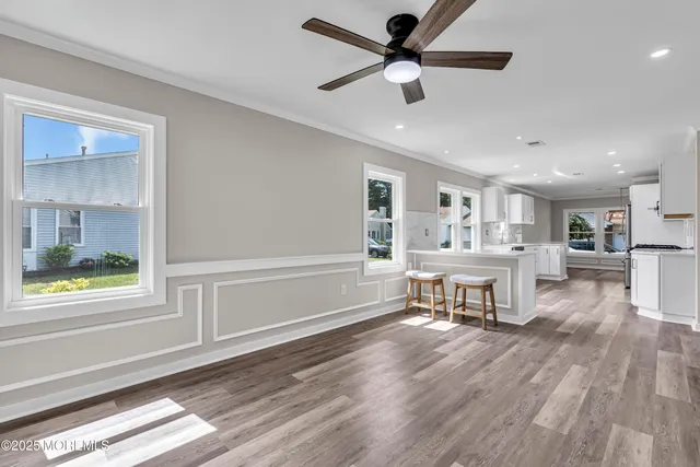 an empty room with wooden floor ceiling fan and windows