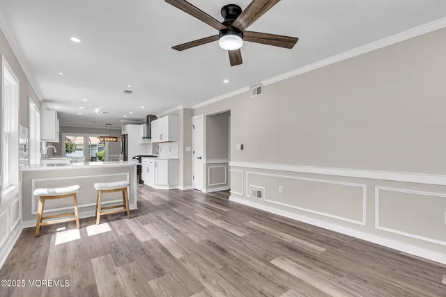 an empty room with wooden floor fan and windows