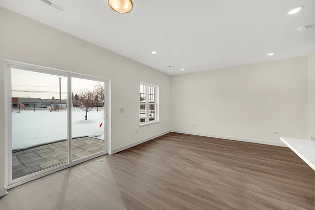 a view of an empty room with wooden floor and windows