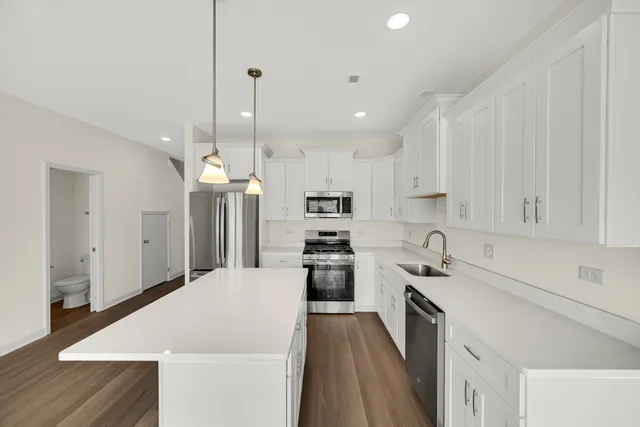 a kitchen with a refrigerator a sink and white cabinets