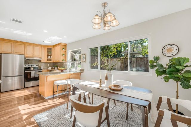 a kitchen with a table chairs a refrigerator and a stove top oven