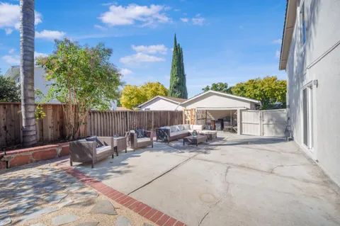 a view of a patio with a table and chairs under an umbrella with wooden fence