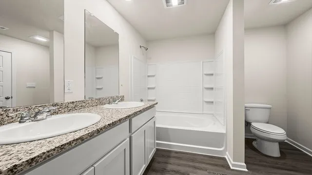 a bathroom with a granite countertop sink a toilet and shower