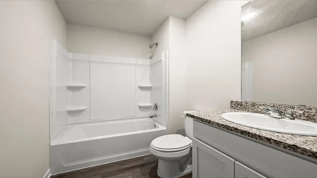 a bathroom with a granite countertop sink a toilet and bathtub