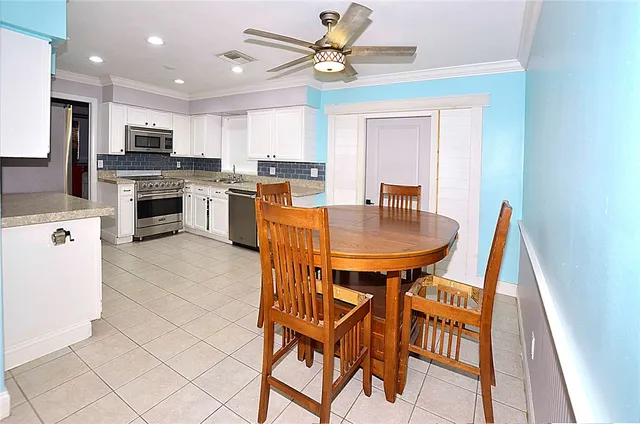 a kitchen with a dining table chairs and refrigerator