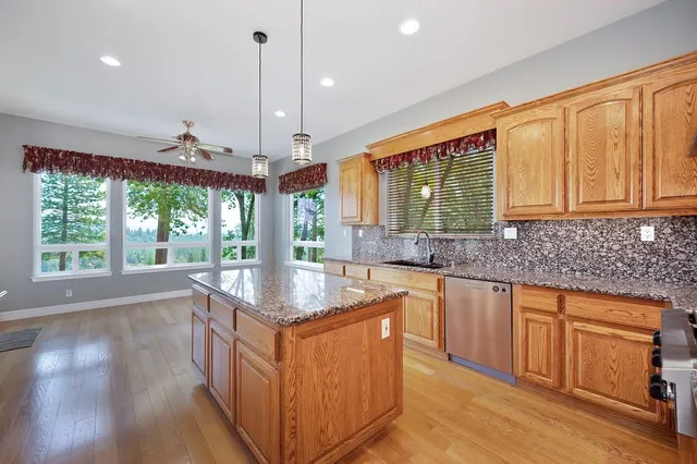 a kitchen with stainless steel appliances granite countertop a sink a stove and a wooden floors