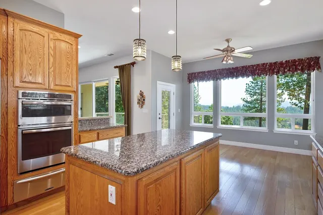 a kitchen with kitchen island granite countertop a stove a sink and wooden floor