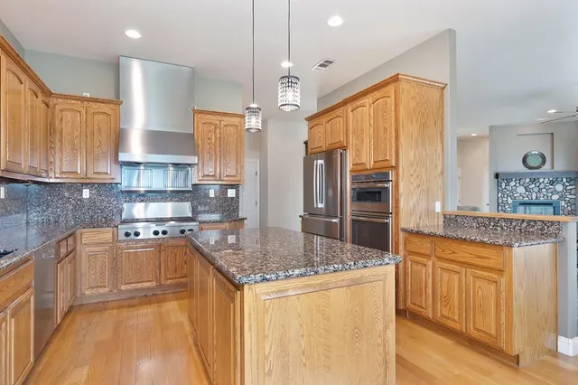 a kitchen with stainless steel appliances granite countertop a sink a stove and a refrigerator