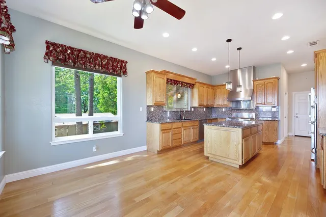 a large kitchen with kitchen island a large window a island and stainless steel appliances