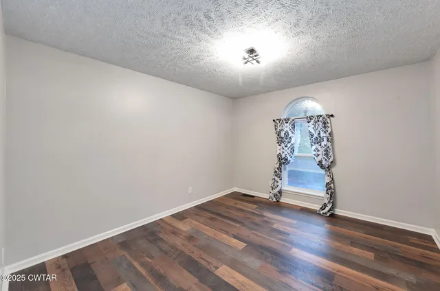 an empty room with wooden floor and chandelier