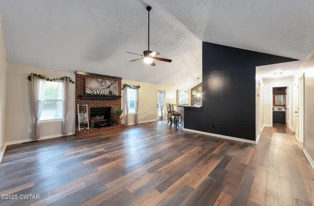 a view of empty room with wooden floor fireplace and a window