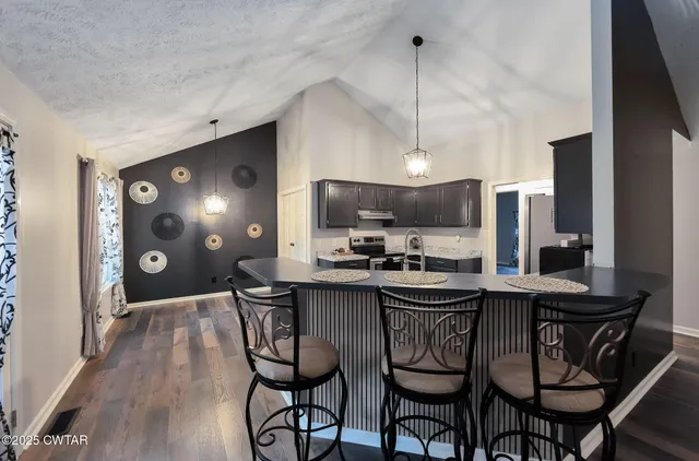 a kitchen with stainless steel appliances a dining table chairs and white cabinets