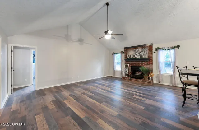 a view of empty room with wooden floor fireplace and window