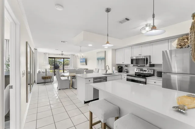 a kitchen with stainless steel appliances kitchen island granite countertop a refrigerator a stove a sink dishwasher a dining table and chairs with wooden floor