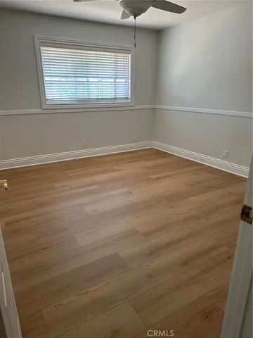 an empty room with wooden floor fan and windows