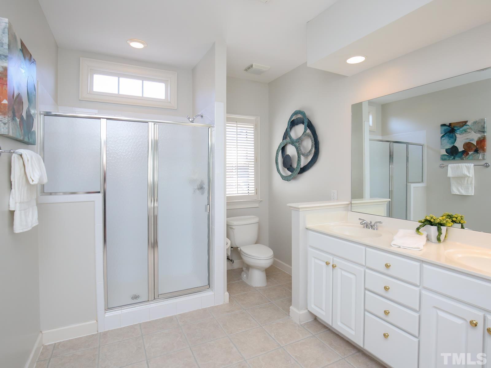 3905 Bentley Meadow Lane Raleigh, NC 27612 - Photo 30 of 40 a bathroom with a toilet a sink and a large mirror