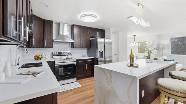 a kitchen with stainless steel appliances kitchen island granite countertop a sink stove and refrigerator