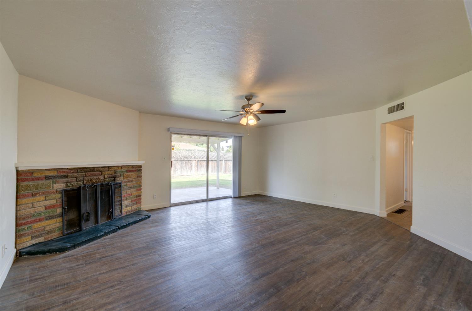 3955 North Tollhouse Road Fresno, CA 93726 - Photo 5 of 17 an empty room with wooden floor fireplace and windows