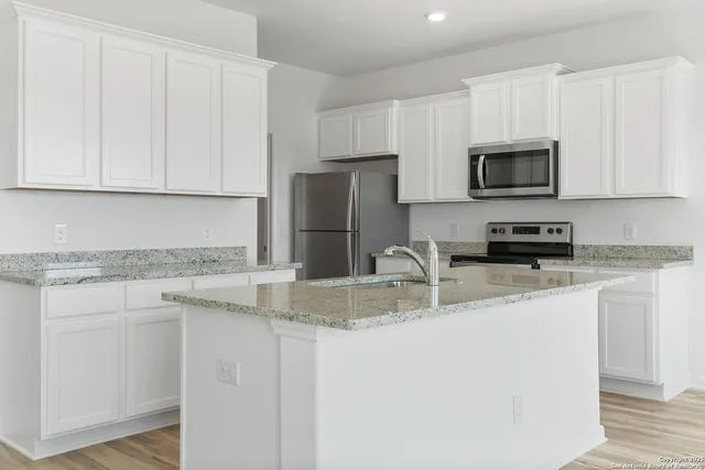 a kitchen with stainless steel appliances granite countertop a sink a stove a microwave and a refrigerator