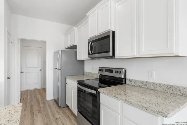 a kitchen with stainless steel appliances granite countertop a stove a microwave and a white cabinets