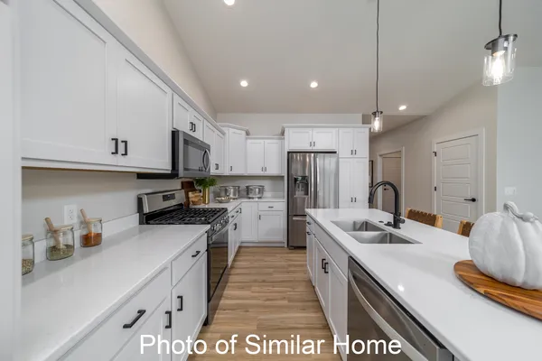 a kitchen with stainless steel appliances a sink a stove a refrigerator and cabinets