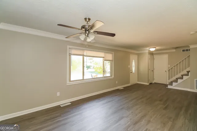 a view of an empty room with wooden floor and a window