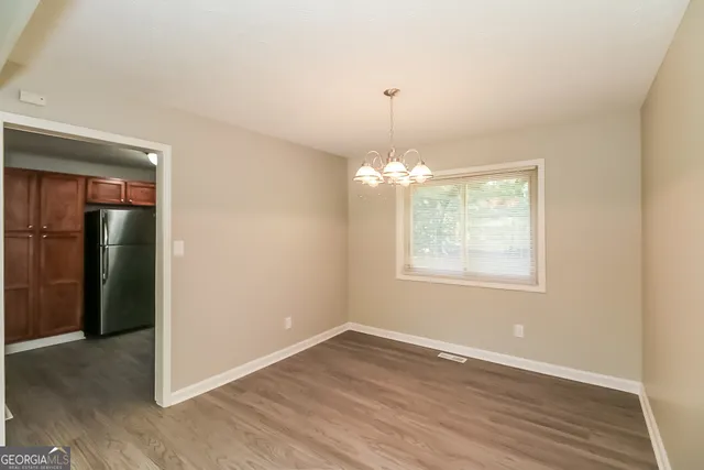 an empty room with wooden floor and chandelier
