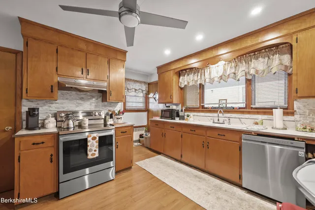 a kitchen with stainless steel appliances granite countertop a stove a sink and white cabinets