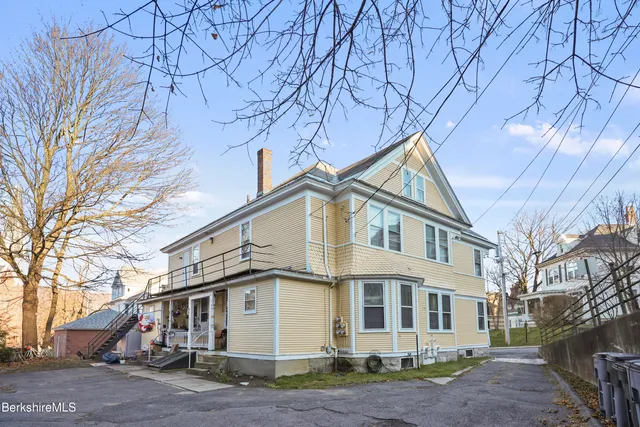 a view of a white house with a large tree
