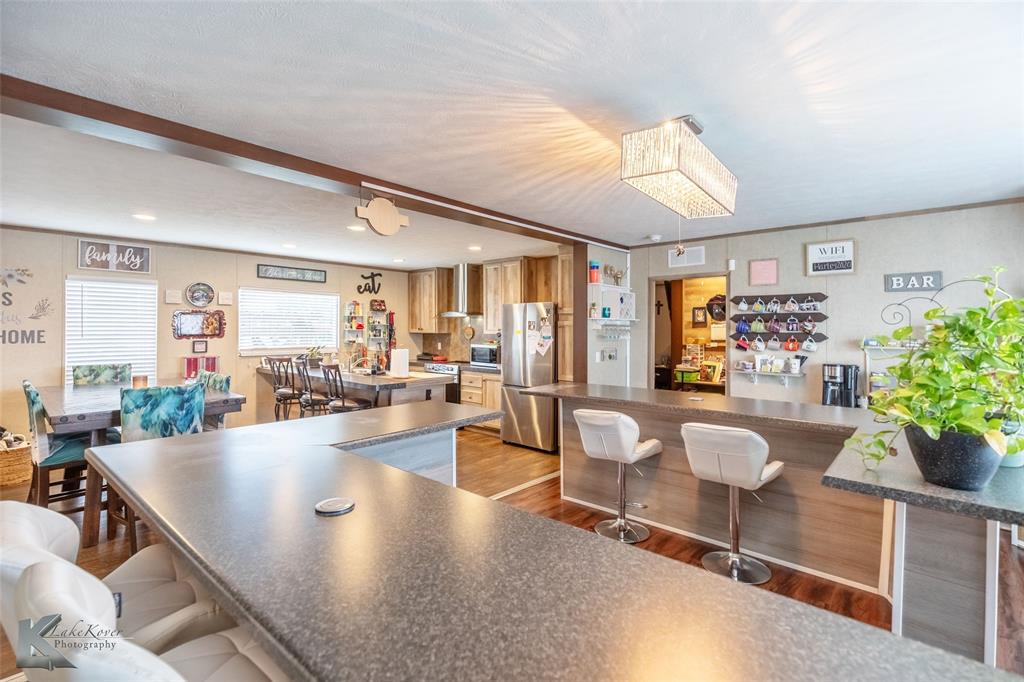 1301 Roma Lane Abilene, TX 79603 - Photo 8 of 20 Kitchen with appliances with stainless steel finishes, a kitchen bar, light wood-type flooring, dark countertops, and recessed lighting