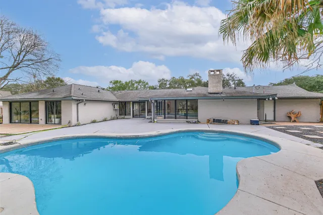 a view of house with swimming pool and a yard