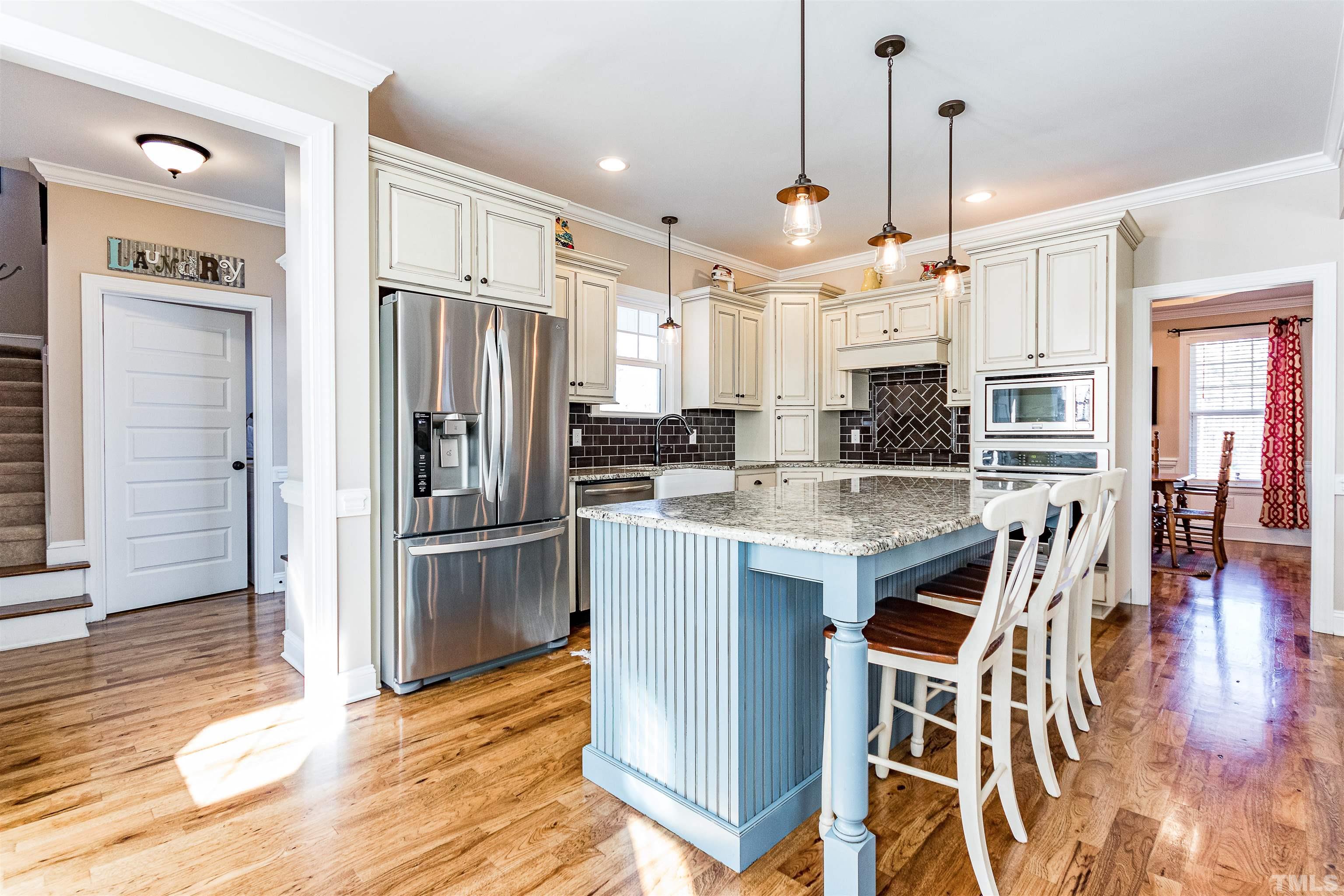 4300 Debnam Road Zebulon, NC 27597 - Photo 29 of 54 a kitchen with stainless steel appliances kitchen island granite countertop a refrigerator a stove a oven and white cabinets with wooden floor