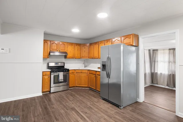 a kitchen with stainless steel appliances granite countertop a refrigerator a stove top oven a sink and dishwasher with wooden floor