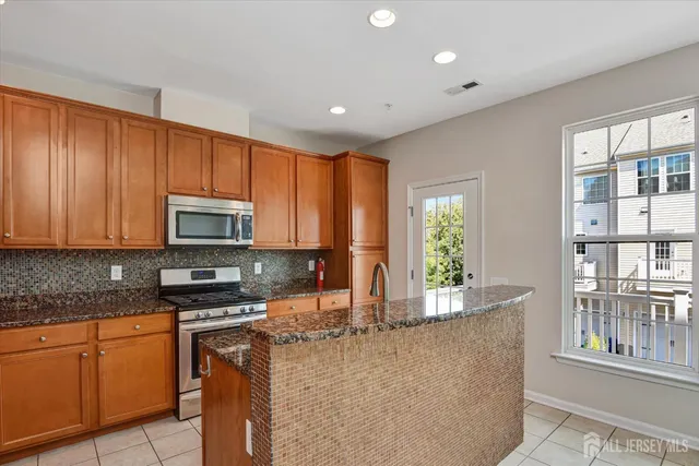 a kitchen with stainless steel appliances granite countertop a stove a sink a microwave a refrigerator and cabinets