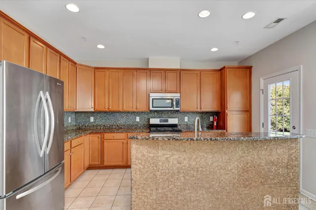 a kitchen with stainless steel appliances granite countertop a refrigerator sink and microwave