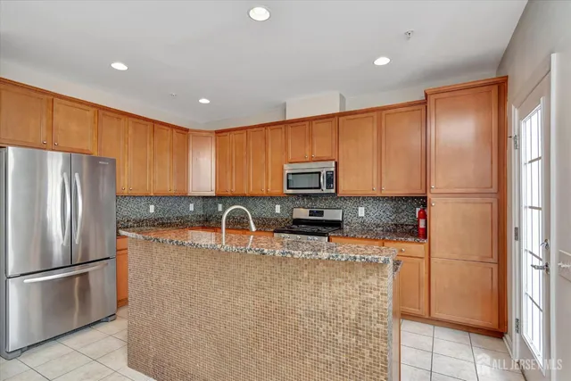 a kitchen with stainless steel appliances granite countertop a refrigerator a stove a sink and a refrigerator