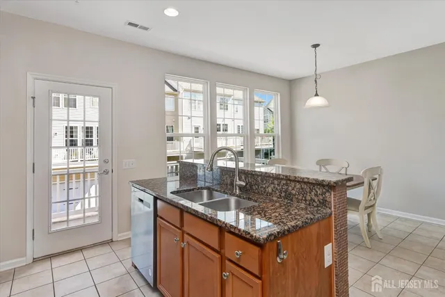 a kitchen with granite countertop a sink a center island and windows